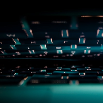 a laptop with a lighted keyboard left slightly open with the light reflecting on the screen