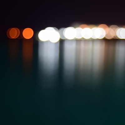 blurred lights in white and orange reflected across water